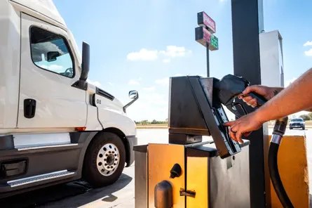 A person pumps diesel next to a semi truck