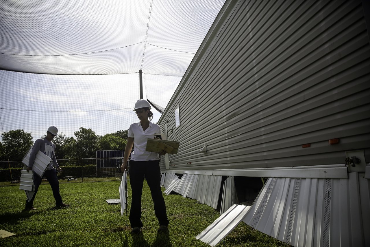 A woman stands near a manufactured home in a testing field for wind