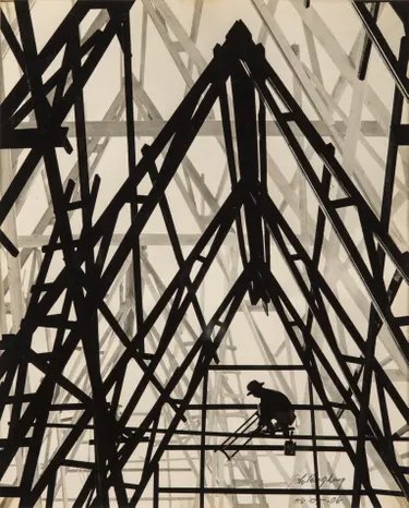 A worker crouches silhouetted amid towering criss-crossed steel construction beams
