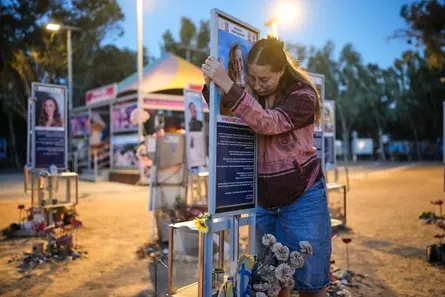 Raz Zarfati rests her head against her sister's memorial photo at the Nova festival site