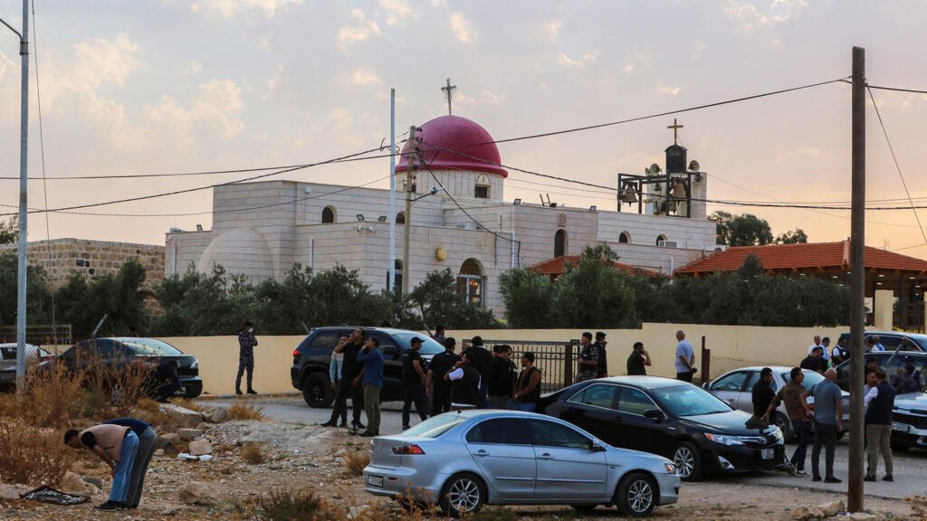 People and security forces gather outside a Church in the village of Hammoud in Jordan's Karak governorate following a shooting on October 23, 2026.