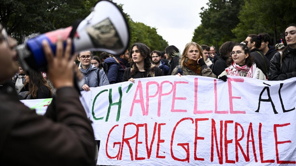 A protester shouts slogans in a megaphone as others hold a banner during a demonstration over learning conditions in Paris on October 22, 2022