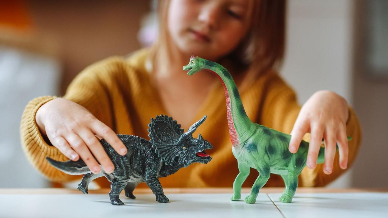 A child playing with plastic toy dinosaurs