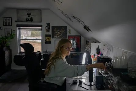 woman sits at desk and reaches into drawer
