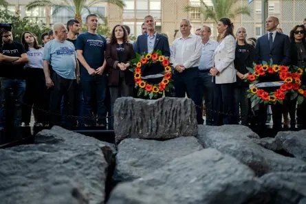 Yair Golan and party members stand solemnly behind a memorial wreath at Rabin Square