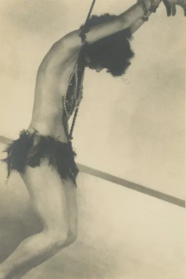 female figure in revealing costume seen in profile, her hands bound and raised above her