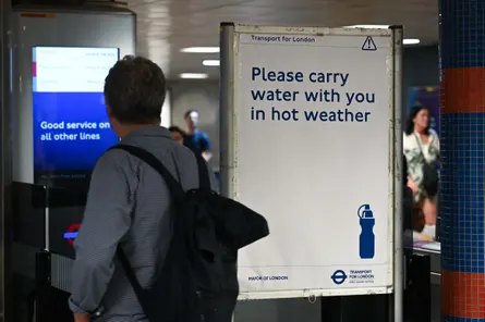 A commuter walks past a London Underground sign urging people to carry water in hot weather