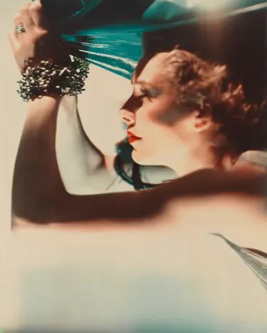 Mrs Richard Hart-Davis, as Ariel, raises her bangled arm holding teal fabric overhead