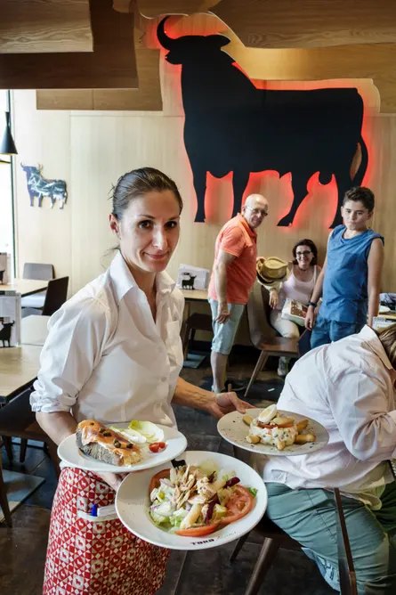 A waitress brings dishes to a table in a Madrid restaurant.